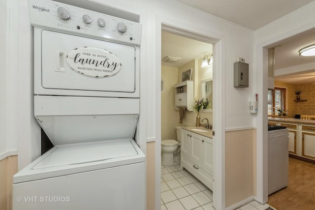 laundry area featuring laundry area, a sink, and stacked washer and clothes dryer