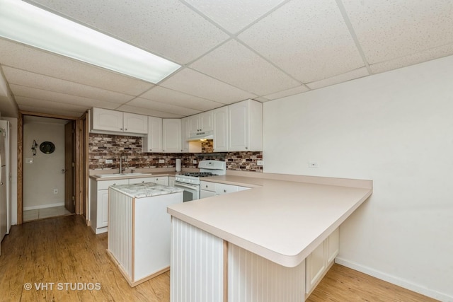 kitchen with light wood finished floors, a kitchen island, light countertops, white gas stove, and under cabinet range hood