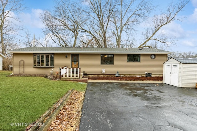 ranch-style home with an outbuilding, driveway, a front yard, and a storage unit