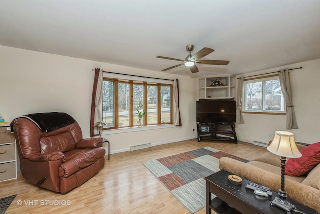 living area with ceiling fan, wood finished floors, visible vents, and baseboards