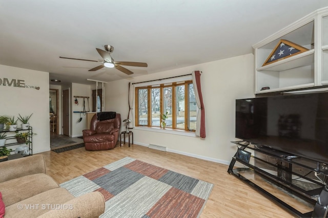 living area featuring a ceiling fan, wood finished floors, visible vents, and baseboards