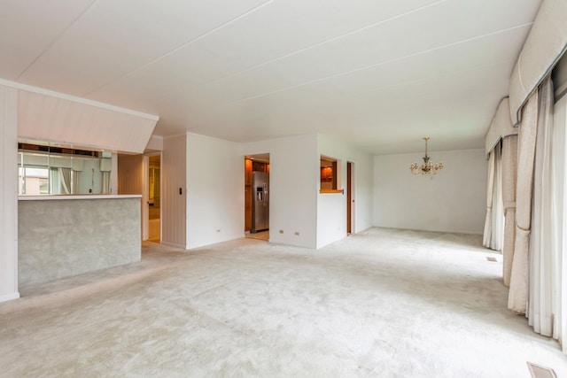 unfurnished living room featuring light carpet and a notable chandelier