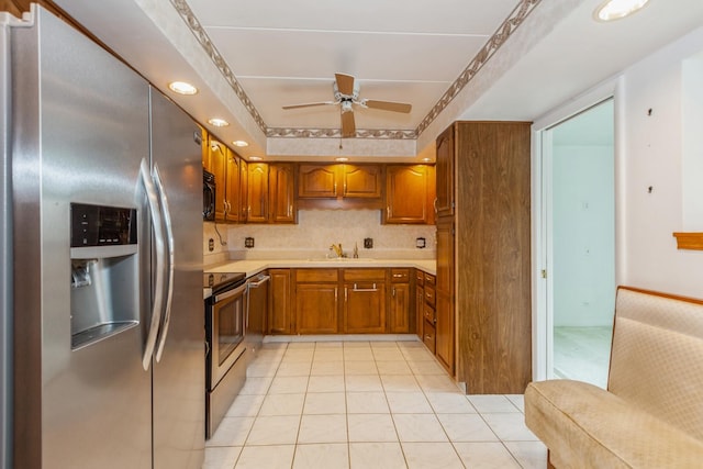 kitchen featuring ceiling fan, a sink, brown cabinets, light countertops, and appliances with stainless steel finishes