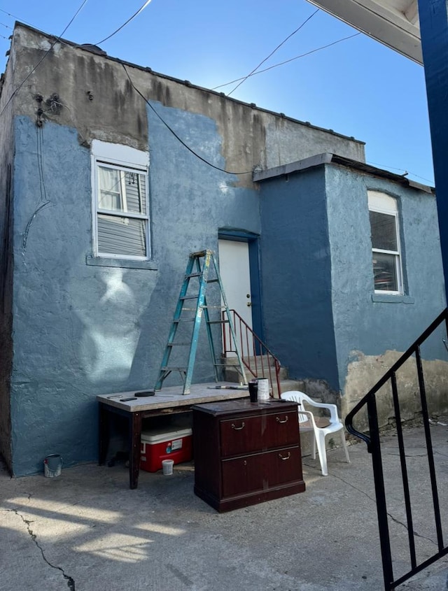 rear view of house featuring stucco siding