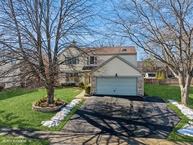 traditional-style home featuring aphalt driveway, a front lawn, fence, and an attached garage