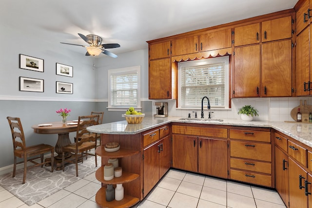 kitchen featuring tasteful backsplash, brown cabinetry, a peninsula, open shelves, and a sink