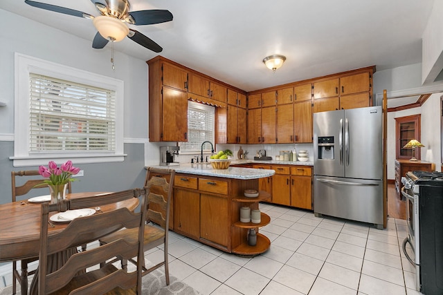 kitchen with stainless steel appliances, brown cabinetry, and light tile patterned flooring