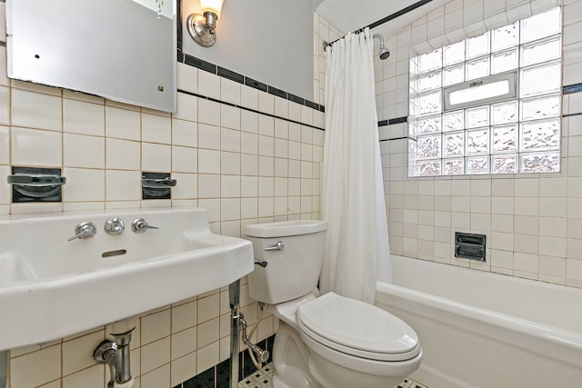 bathroom with tile walls, toilet, and shower / bath combo with shower curtain