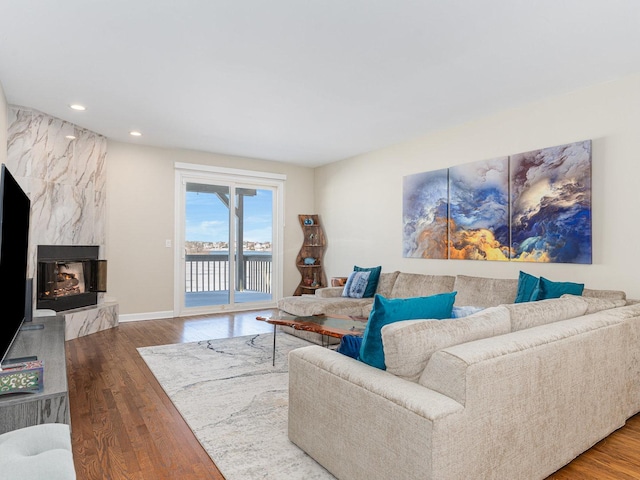 living room with recessed lighting, baseboards, wood finished floors, and a high end fireplace