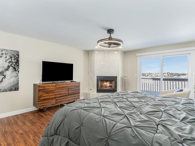 bedroom with access to outside, wood finished floors, a high end fireplace, and baseboards