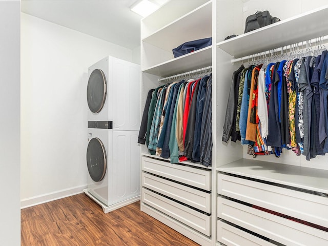 spacious closet featuring stacked washing maching and dryer and wood finished floors