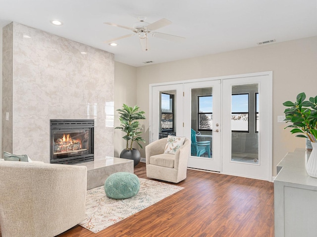 living room with a high end fireplace, a wealth of natural light, visible vents, and wood finished floors