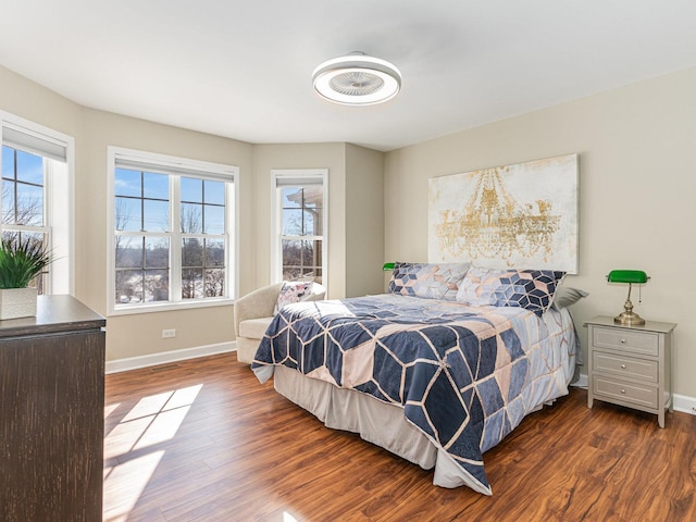 bedroom with multiple windows, wood finished floors, and baseboards