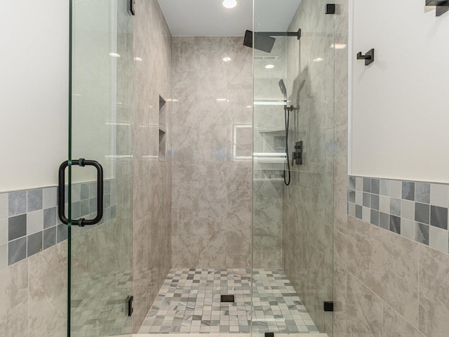 full bath featuring a shower stall and tile walls