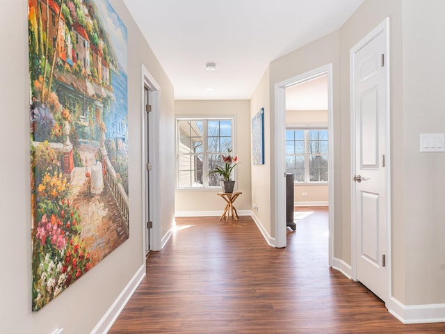 hallway featuring dark wood-type flooring and baseboards