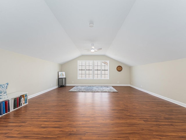 bonus room featuring dark wood-type flooring, vaulted ceiling, baseboards, and a ceiling fan