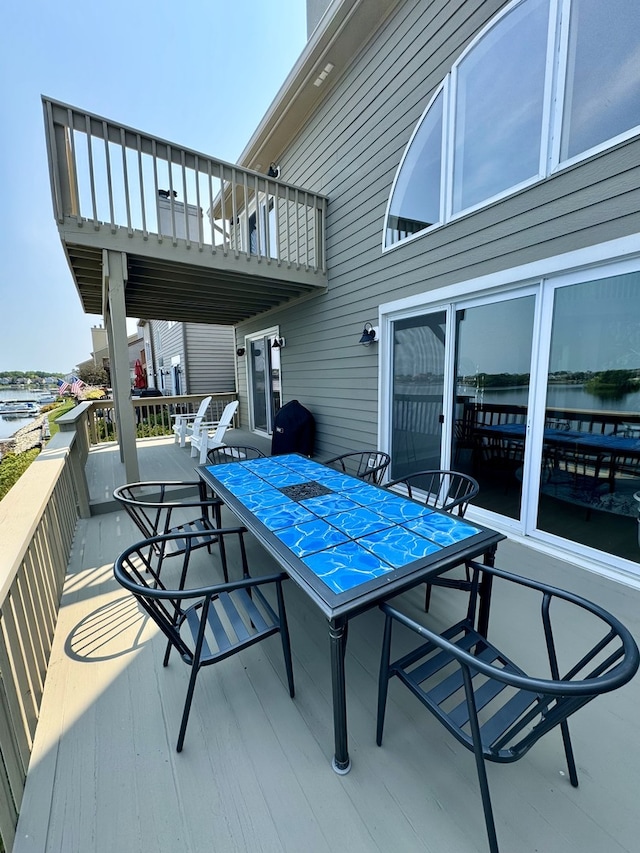 exterior space with outdoor dining space and a deck with water view