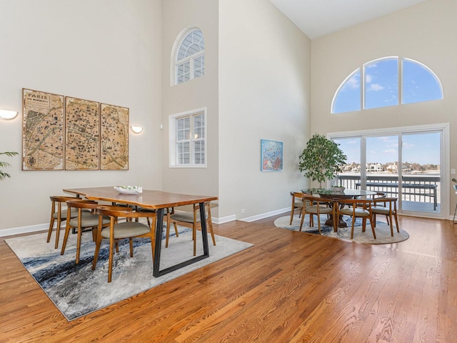 dining area with a high ceiling, baseboards, and wood finished floors