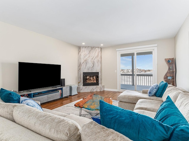 living room featuring a fireplace, baseboards, wood finished floors, and recessed lighting