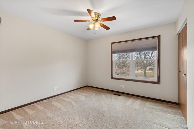 spare room featuring carpet, visible vents, ceiling fan, and baseboards