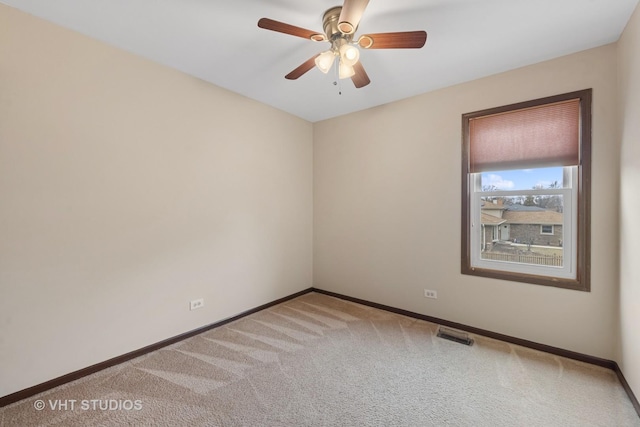 carpeted empty room featuring a ceiling fan, visible vents, and baseboards