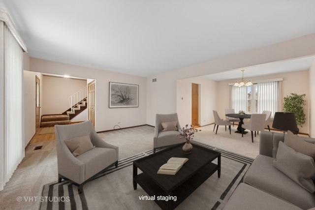 carpeted living area featuring a chandelier, visible vents, and stairs