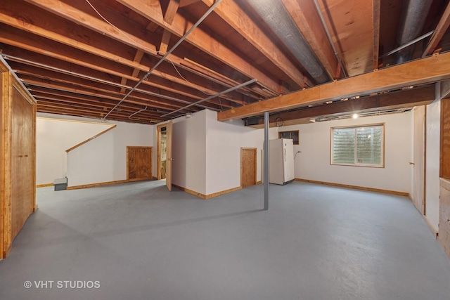 basement with freestanding refrigerator and baseboards