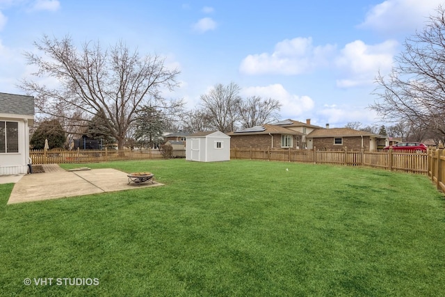 view of yard with an outbuilding, a patio, a storage shed, an outdoor fire pit, and a fenced backyard