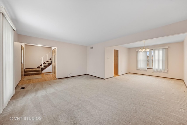 unfurnished living room with light carpet, a notable chandelier, visible vents, and stairs