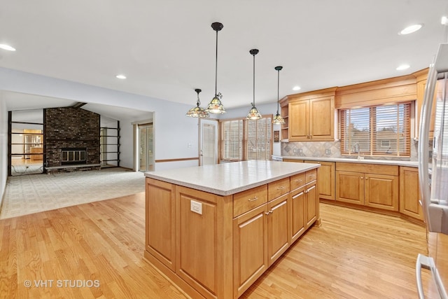 kitchen featuring a center island, a fireplace, light countertops, light wood-style flooring, and decorative backsplash