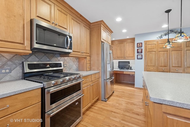 kitchen with decorative backsplash, hanging light fixtures, stainless steel appliances, light wood-type flooring, and built in desk