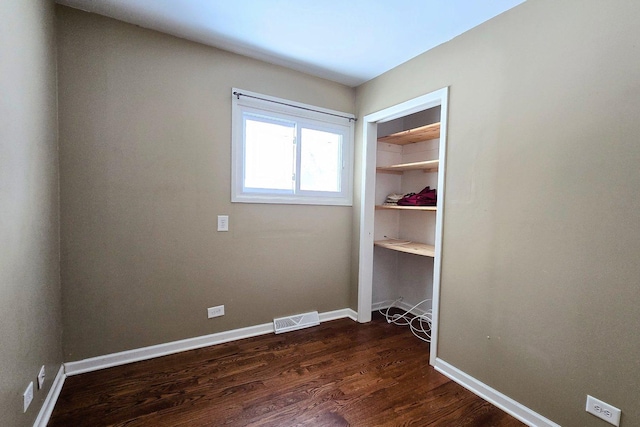 spare room with dark wood finished floors, visible vents, and baseboards