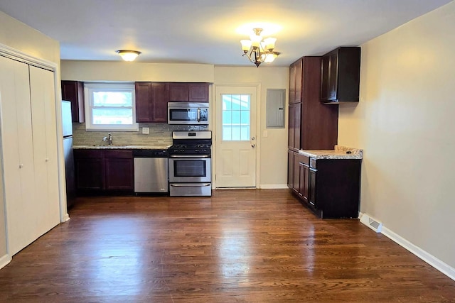 kitchen featuring light stone counters, stainless steel appliances, backsplash, dark wood-type flooring, and a sink