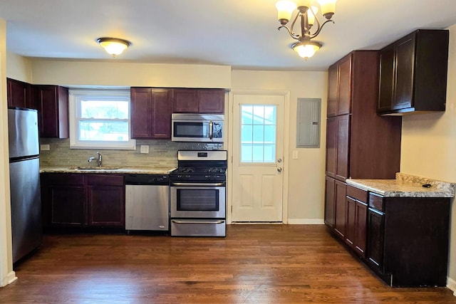 kitchen with light stone countertops, dark wood-style flooring, stainless steel appliances, and a sink