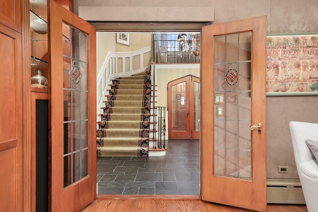 foyer entrance featuring a baseboard heating unit, stairway, and wood finished floors