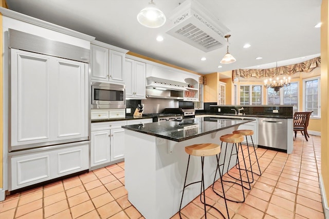 kitchen featuring built in appliances, a notable chandelier, a peninsula, white cabinetry, and backsplash