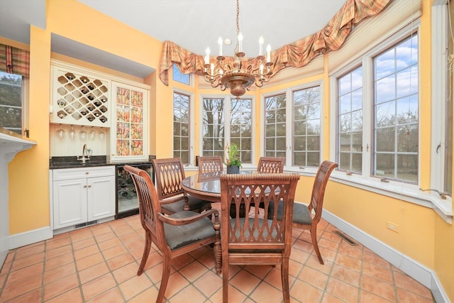 dining space with light tile patterned floors, wine cooler, baseboards, and an inviting chandelier