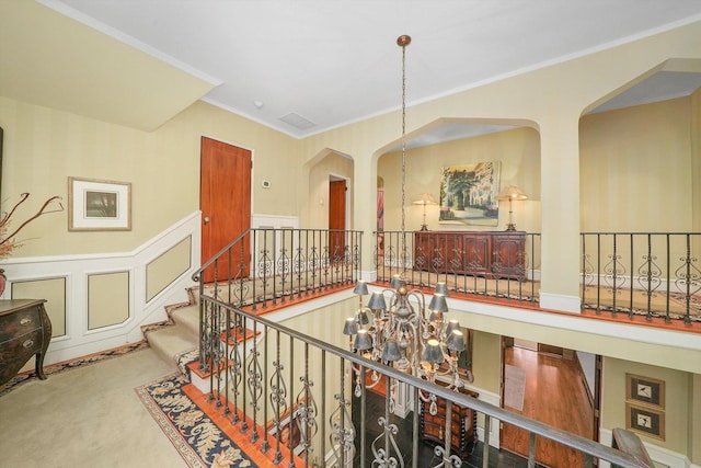 hallway featuring a chandelier, a wainscoted wall, carpet flooring, and crown molding