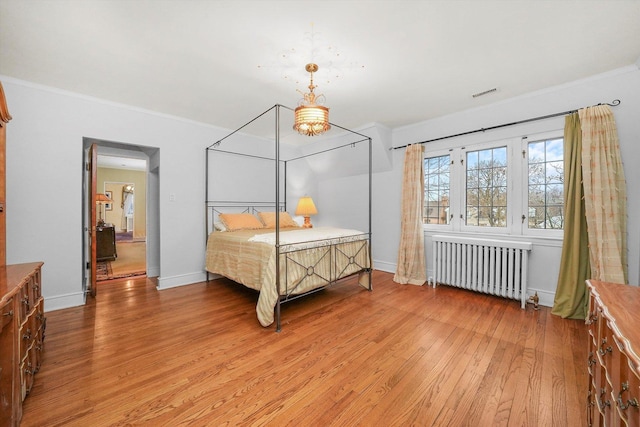 bedroom featuring crown molding, radiator, visible vents, light wood-style flooring, and baseboards