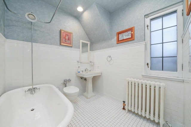 bathroom featuring a soaking tub, radiator heating unit, vaulted ceiling, and tile patterned flooring