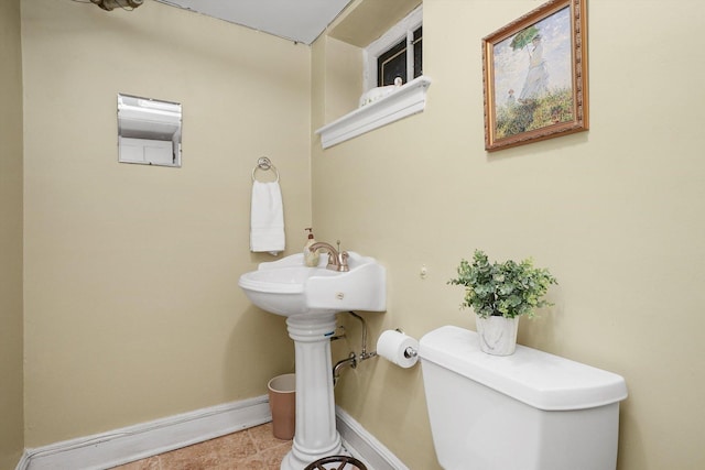 half bathroom with tile patterned floors, toilet, and baseboards