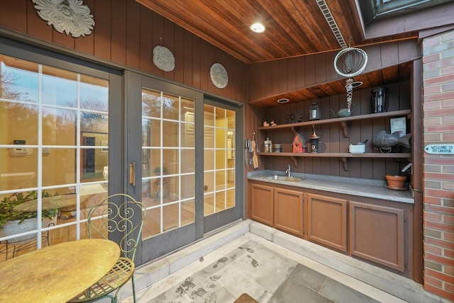 bar with wood walls, wood ceiling, vaulted ceiling, and a sink