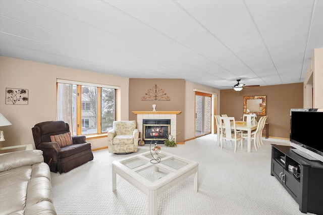 living room with carpet floors, a fireplace, baseboards, and a ceiling fan