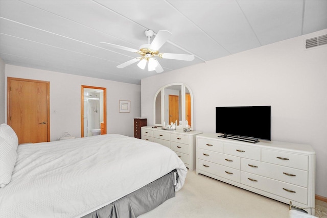 bedroom with ceiling fan, arched walkways, light carpet, visible vents, and ensuite bath