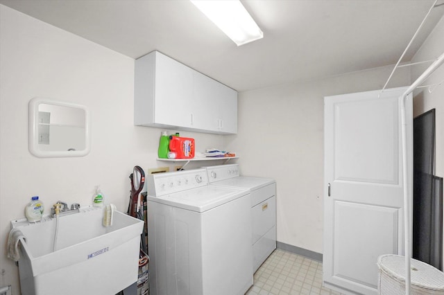 washroom featuring washer and dryer, cabinet space, a sink, and baseboards