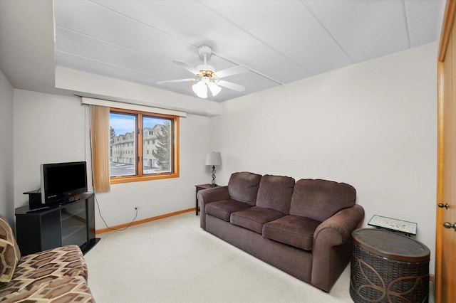 living area with ceiling fan, baseboards, and light colored carpet