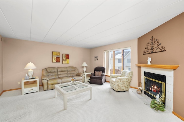 carpeted living room featuring baseboards and a tiled fireplace