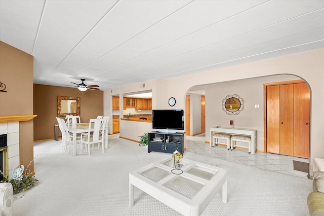 living room with arched walkways, a fireplace, and light carpet