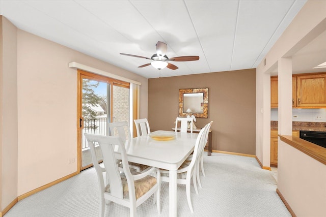 dining room with light carpet, ceiling fan, and baseboards