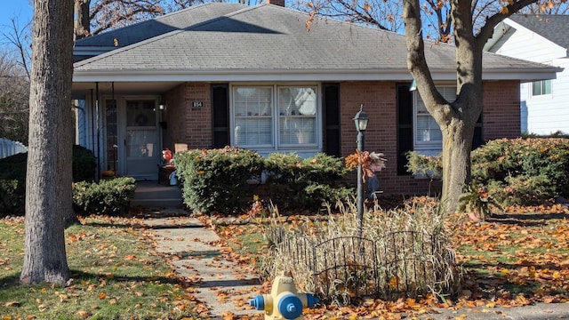 view of front of home with brick siding and roof with shingles